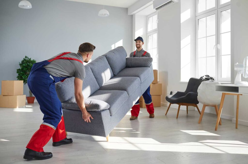 two-young-workers-lift-heavy-sofa